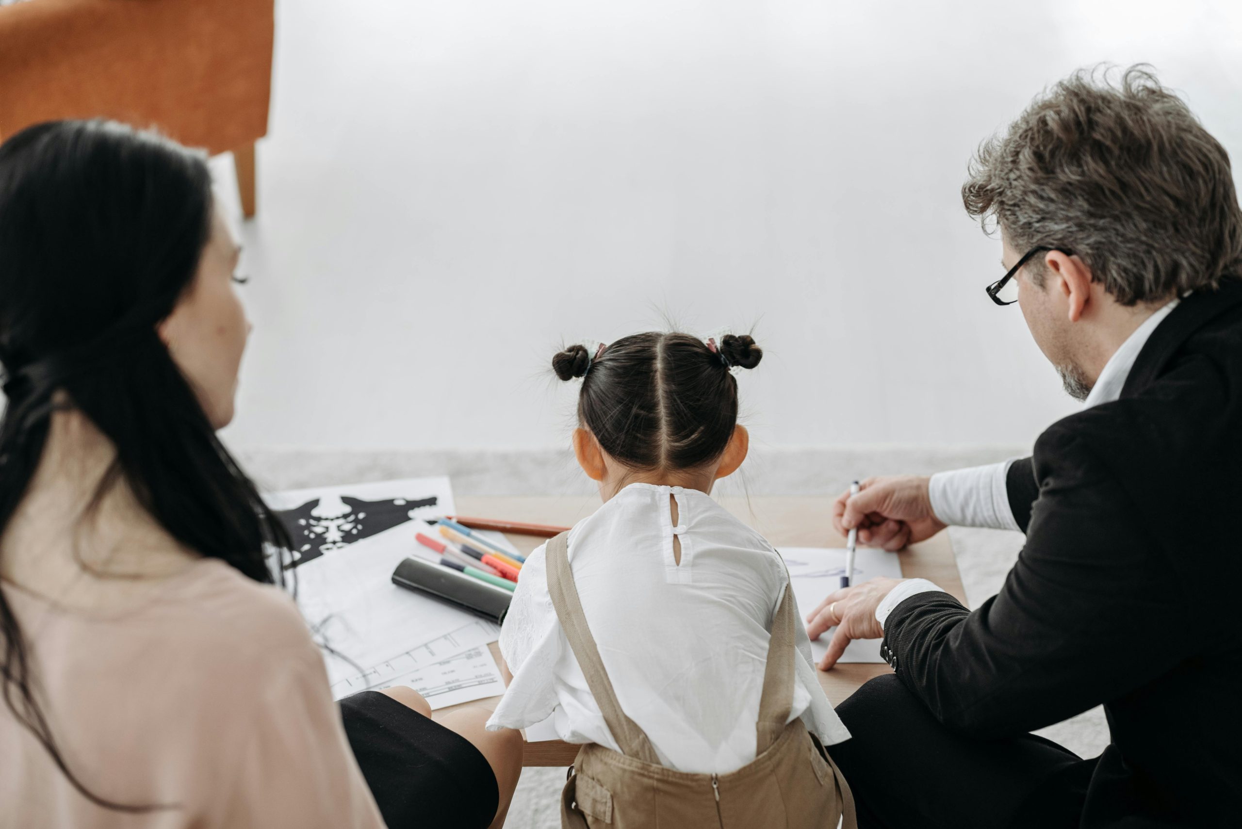 two adults and toddler from behind, playing, colouring in